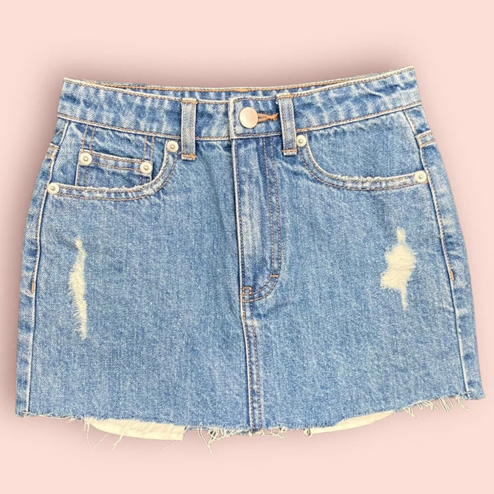 Katie J NYC’s junior's Miami denim skirt with a frayed raw-cut hem and a 5-pocket design, in a medium wash.