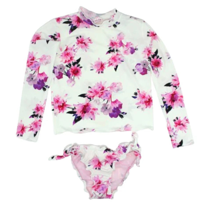 The Alessandra  rashguard bikini set from Piccoli Principi with long sleeves, featuring a Pink & Purple floral pattern on a white background. The bottom of the set has a side ties.